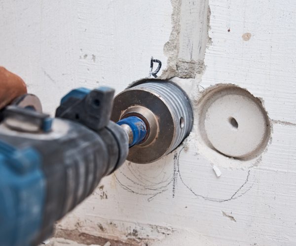 Builder with hummer drill perforator drills hole in a wall