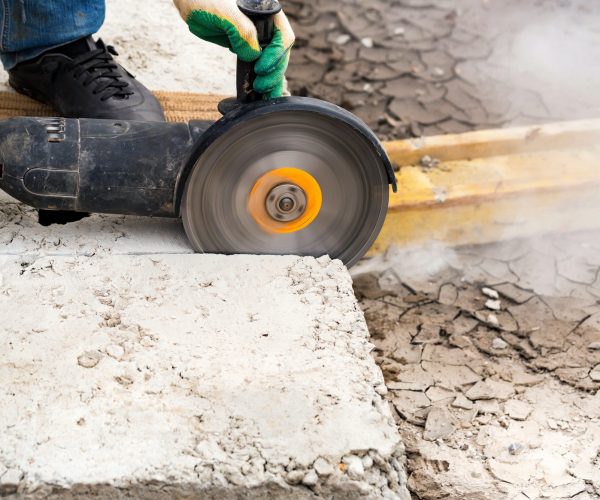 Close up worker cuts concrete with circular saw